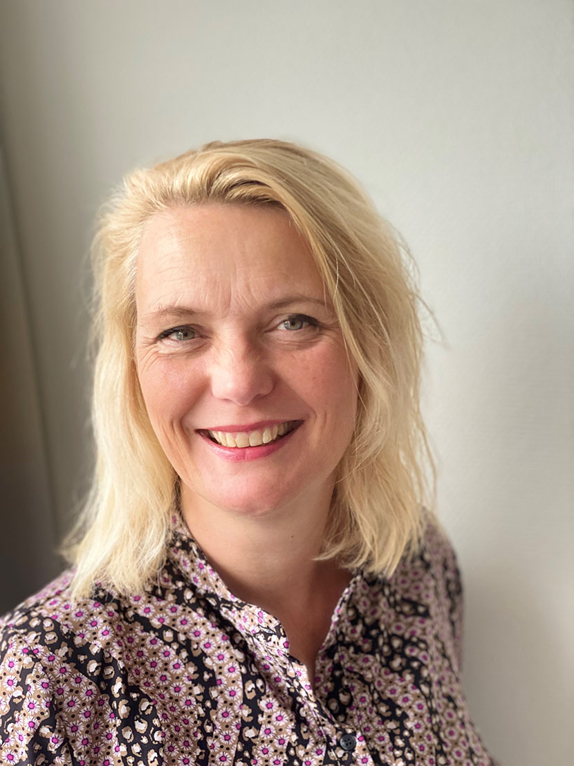 Monochrome image of a woman holding a flower behind her back, artistically posed.